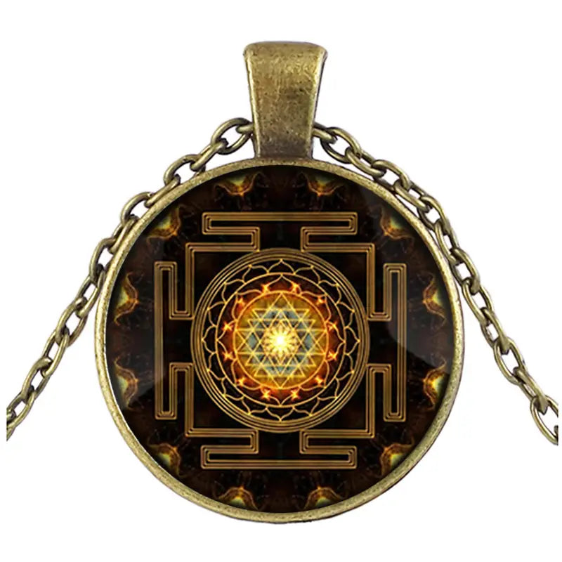 Antique brass pendant necklace featuring a circular glass cabochon with an intricate golden Sri Yantra design on a dark background.
