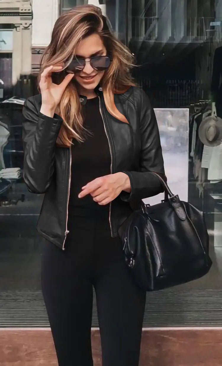 Black leather tote bag with a structured shape and top handle paired with a faux leather bomber jacket fitted zip up coat.