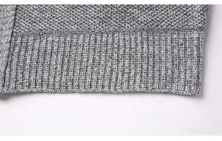Saumbereich eines Herren-Zippstrickcardigans aus grauem Strickstoff mit strukturiertem Diamantmuster und geripptem Abschluss