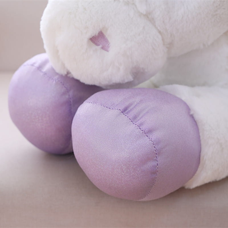 A plush unicorn toy with soft white fur and lavender hooves in pink and purple colors designed as a soft stuffed animal.
