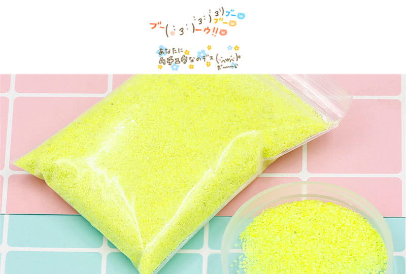 透明なプラスチック袋に入った、鮮やかなネオンイエローのきらめく撥水・防水の魔法の砂。少しこぼれて小さな透明なボウルに入っており、工作用の子ども向け玩具です。