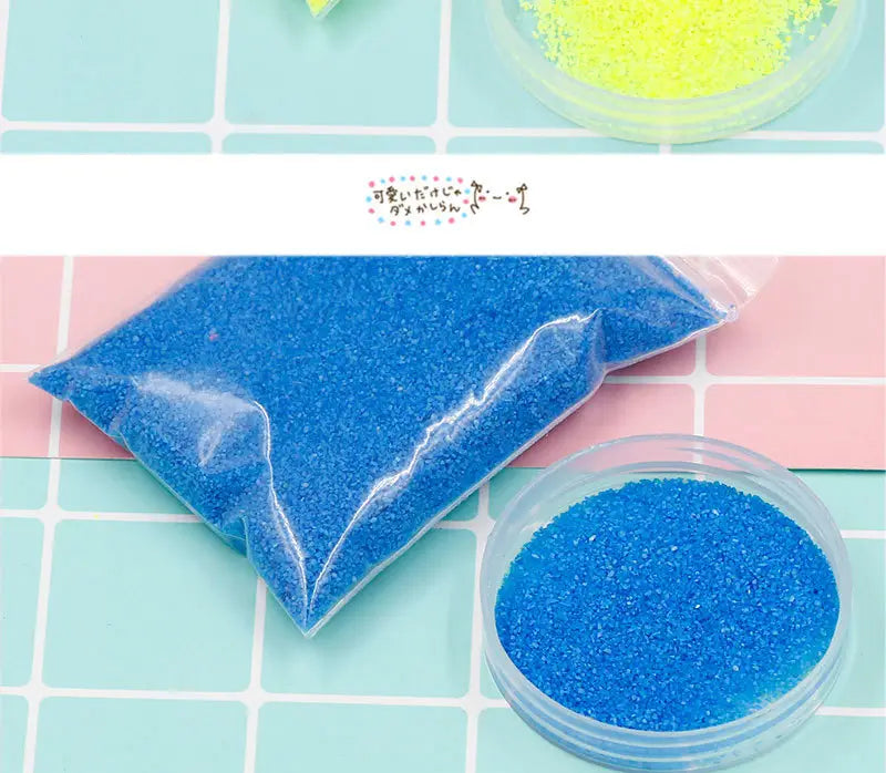 透明なプラスチック袋と、それに合う丸形の容器を備えた、鮮やかな青のきらめく撥水・防水の魔法の砂の子ども向け手作り玩具。クラフトや装飾に適した用途です。