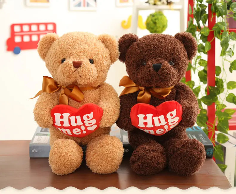 Dos peluches de oso de peluche con aspecto de oso de felpa de 55 cm en colores marrón claro y marrón oscuro, con moños dorados y sosteniendo almohadillas rojas con forma de corazón con el texto «abrázame», con suéteres de punto.