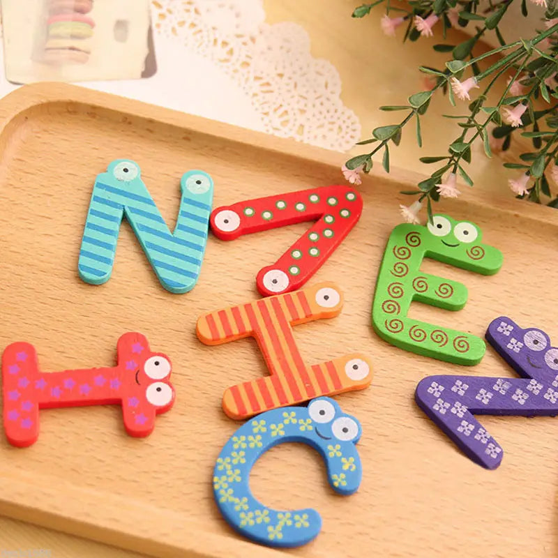 Lettres de l’alphabet en bois magnétique colorées, avec des yeux de dessin animé ludiques et des motifs conçus comme aimants de réfrigérateur pour des jouets pour enfants.