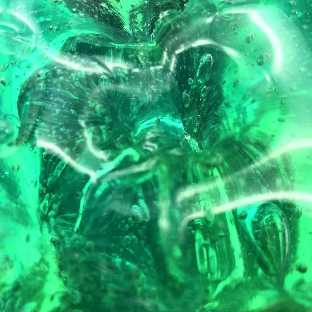 Vibrant green translucent glass sculpture with swirling patterns and embedded bubbles resembling gradient crystal mud slime blue and purple putty toy.