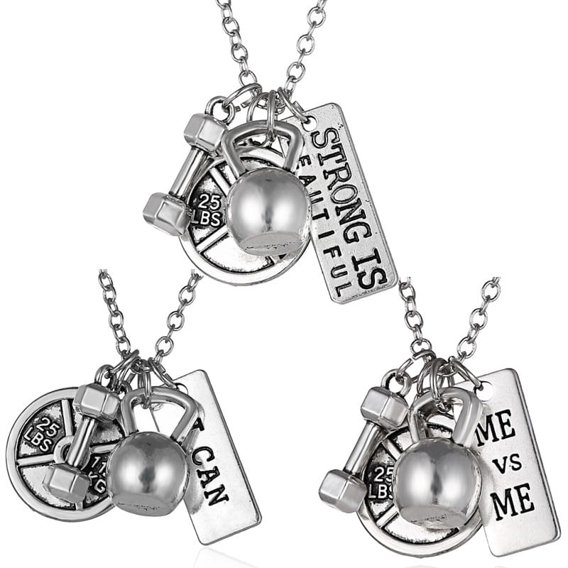 Silver-toned fitness pendant necklace featuring kettlebell dumbbell and weight plate charms with engraved motivational phrases.
