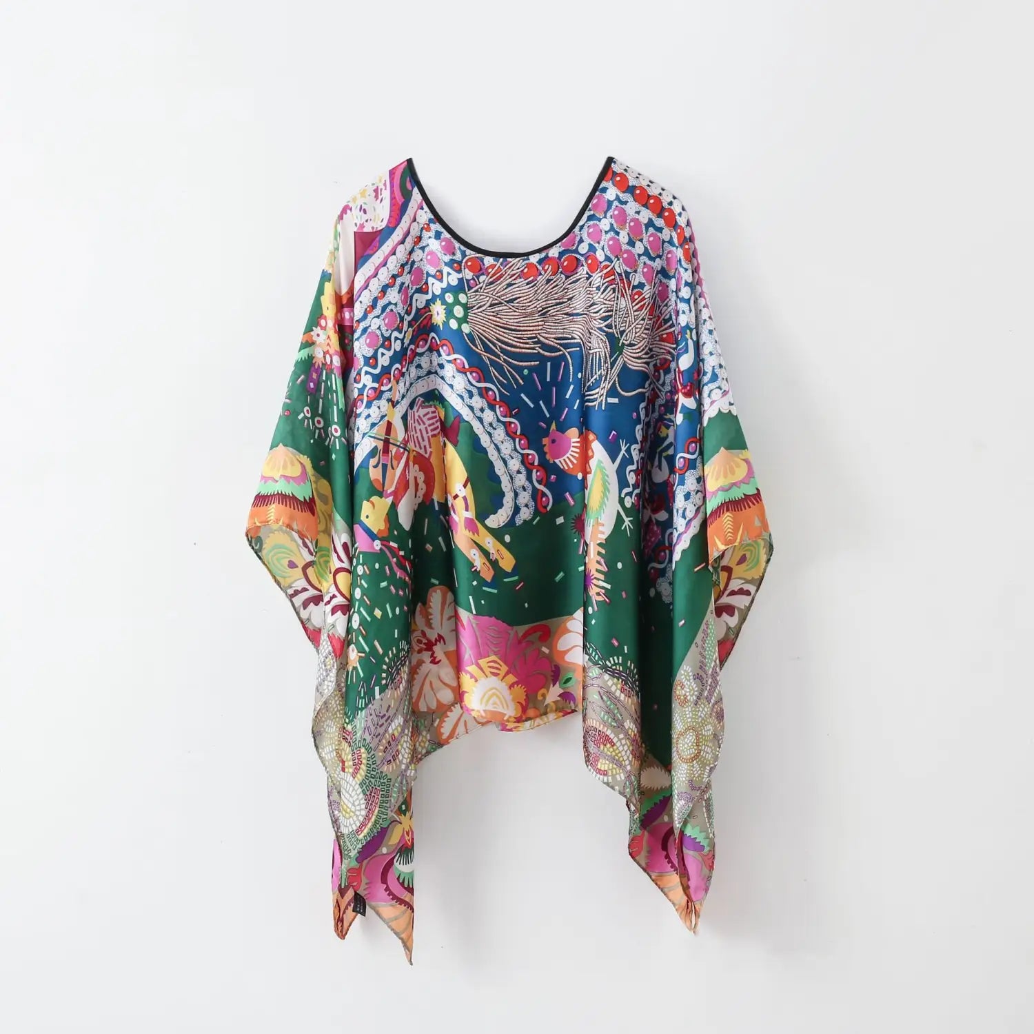 A printed silk patterned pullover shawl cape outerwear featuring a vibrant flowing kaftan-style top in green blue pink and gold hues with an intricate whimsical print of mythical creatures and floral motifs on lightweight fabric.