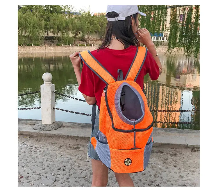 Bright orange and gray dog backpack breathable mesh pet carrier travel bag with mesh panels and a circular logo on the front.
