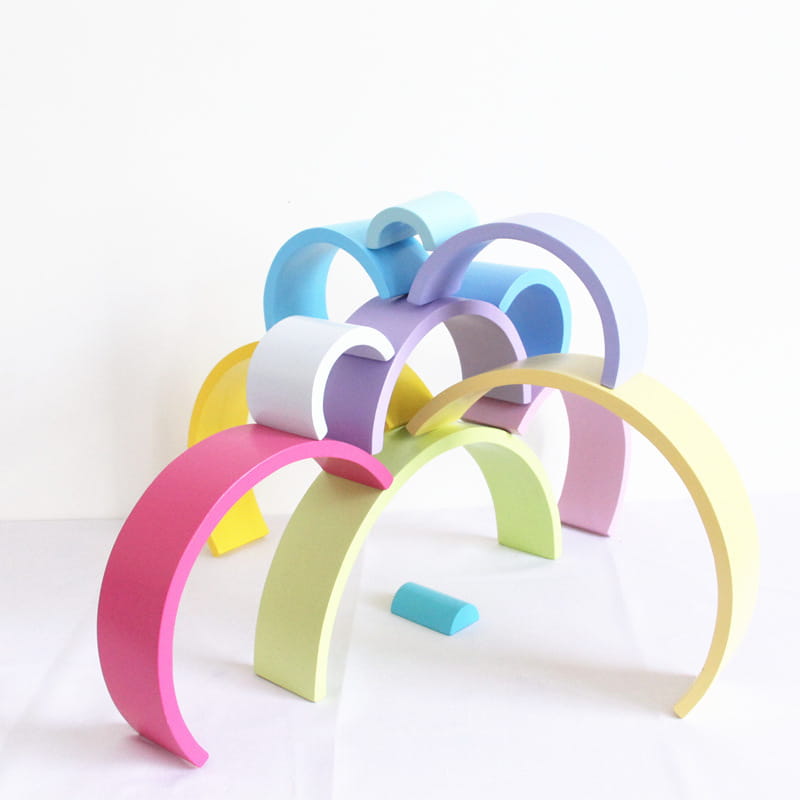 Pastel-colored wooden arches arranged in a playful overlapping rainbow pattern for the rainbow wooden stacking arch bridge 12 piece puzzle toy.