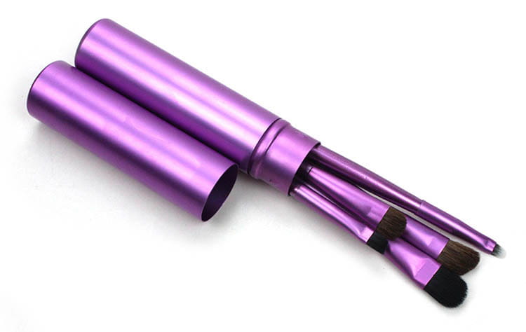 Travel eye makeup brush set with three purple metallic cylindrical brushes featuring black bristles and matching handles in a portable case