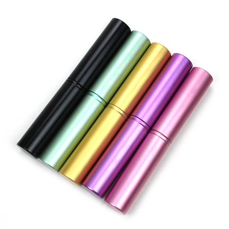 Set of five metallic cylindrical travel perfume bottles in black mint green gold purple and pink for use with travel eye makeup brush set in a portable case.