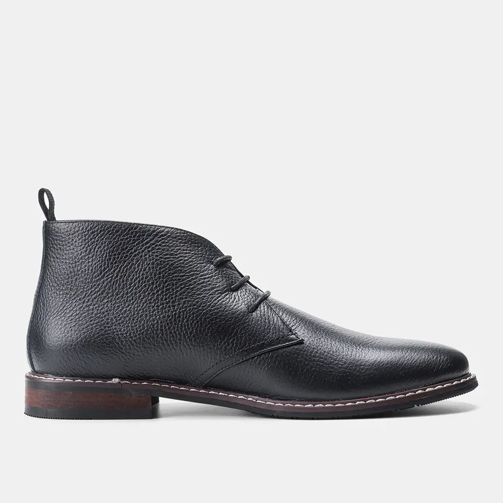 Men’s lychee pattern cowhide Chelsea Martin boots in black leather with textured surface and contrasting white stitching along the sole.