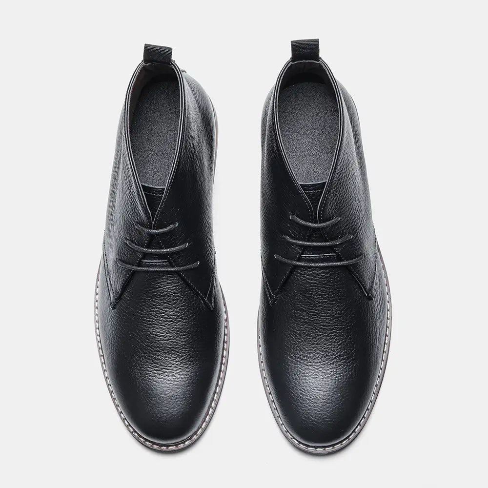 Men’s lychee pattern cowhide Chelsea Martin boots in black leather with textured surface and contrasting white stitching along the sole edge.