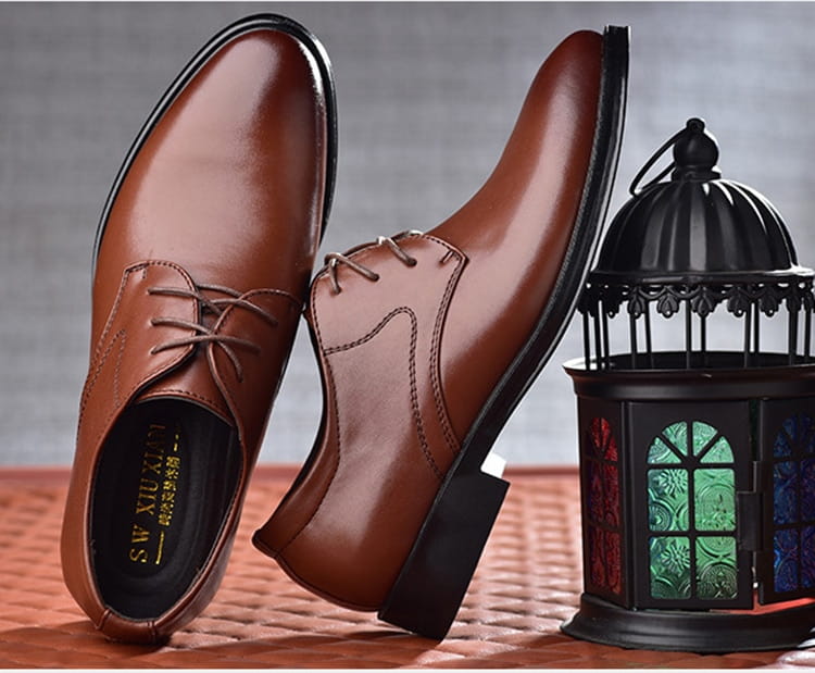 Men’s brown leather oxford dress shoes with black pointed toe soles and laces.
