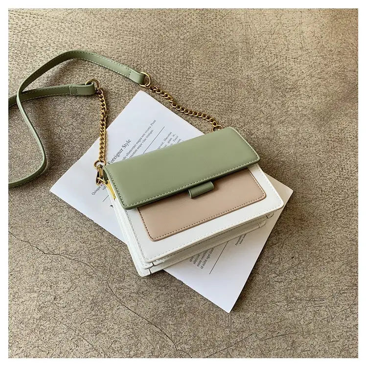 Pastel green and beige two-tone square crossbody bag in faux leather with a gold chain strap.