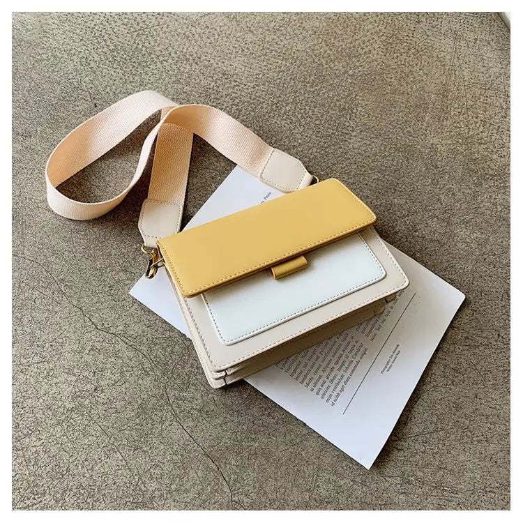 A stylish square crossbody bag with a two-tone design featuring cream white and mustard yellow faux leather panels and a gold chain strap.