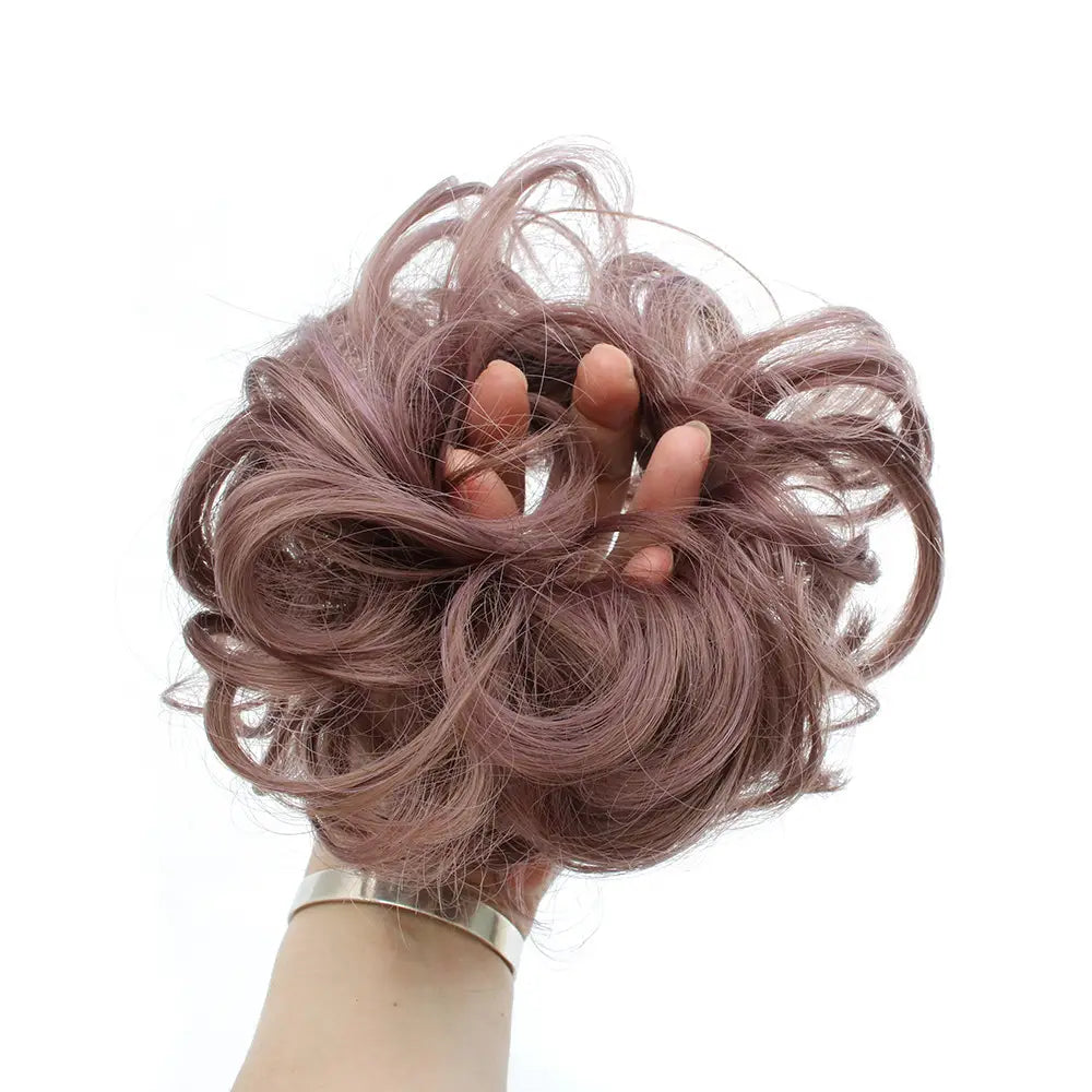 Eine weiche, staubig-rosafarbene, lockige synthetische Haardutt-Erweiterung mit voluminöser Textur aus der Kollektion Curly Synthetic Hair Bun Extension 46 Farben.