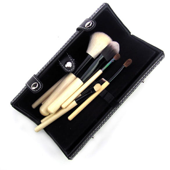 Black leather makeup brush case containing several wooden handled makeup brushes with natural bristles from a 10 piece gold and black makeup brush set.