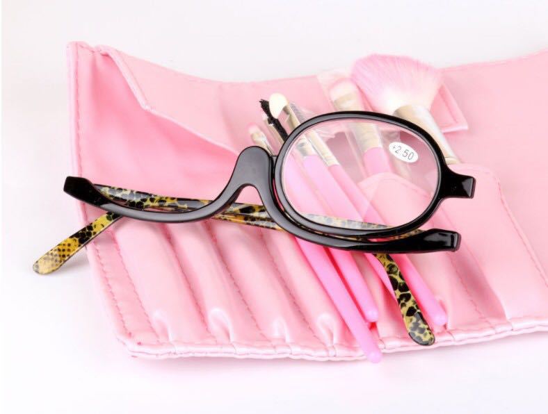 black-framed makeup reading glasses with leopard-print temple tips rest atop a pink makeup brush roll in a plus 2.50 strength variety pack