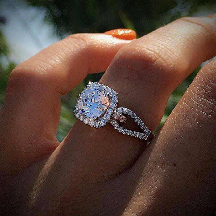 A sparkling silver square cut diamond halo engagement ring featuring a large center diamond surrounded by smaller diamonds with an elegant twisted band design.