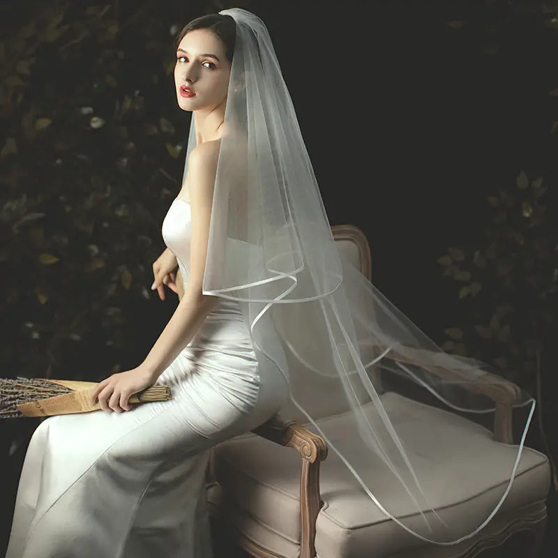 A delicate double layer white tulle short veil with a subtle sheen cascades elegantly down the bride’s back and is secured with a hair comb.