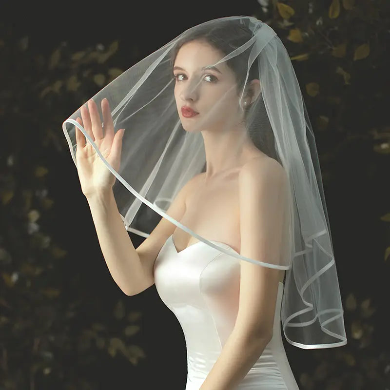 A delicate double layer white tulle short veil with a subtle satin trim and hair comb.