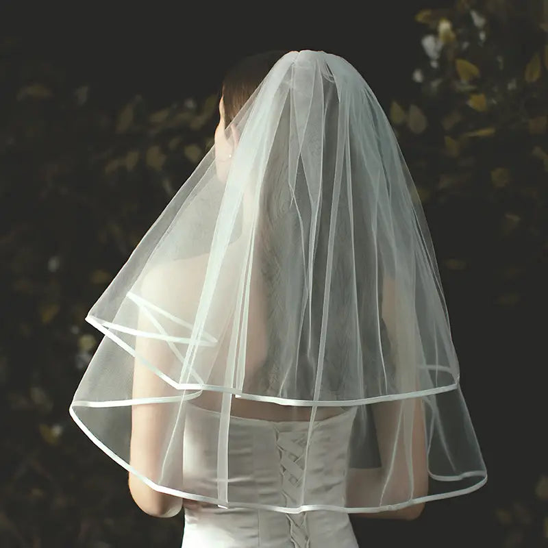 Double layer white tulle short veil with hair comb featuring a delicate multi-tiered design and subtle lace trim along the edges.