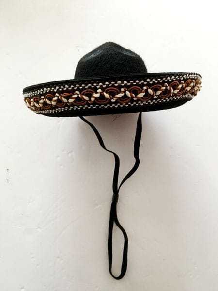 Black knitted dog sombrero hat featuring a decorative braided band with brown white and silver accents for pet costume use.
