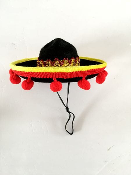 Black felt knitted dog sombrero hat pet costume with a yellow and red embroidered band and red pom-poms along the brim.
