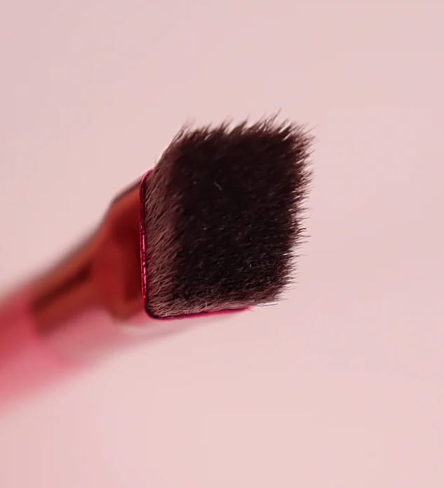 A dense dark brown synthetic eyebrow brush head with a sleek red handle from the eyebrow brush and gel set with pink angled applicator.