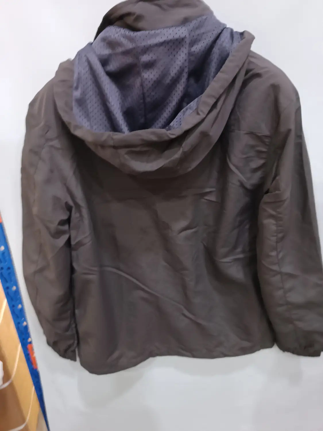 Chaqueta de senderismo con capucha impermeable color gris oscuro, con interior forrado con malla, mostrada desde el lado posterior
