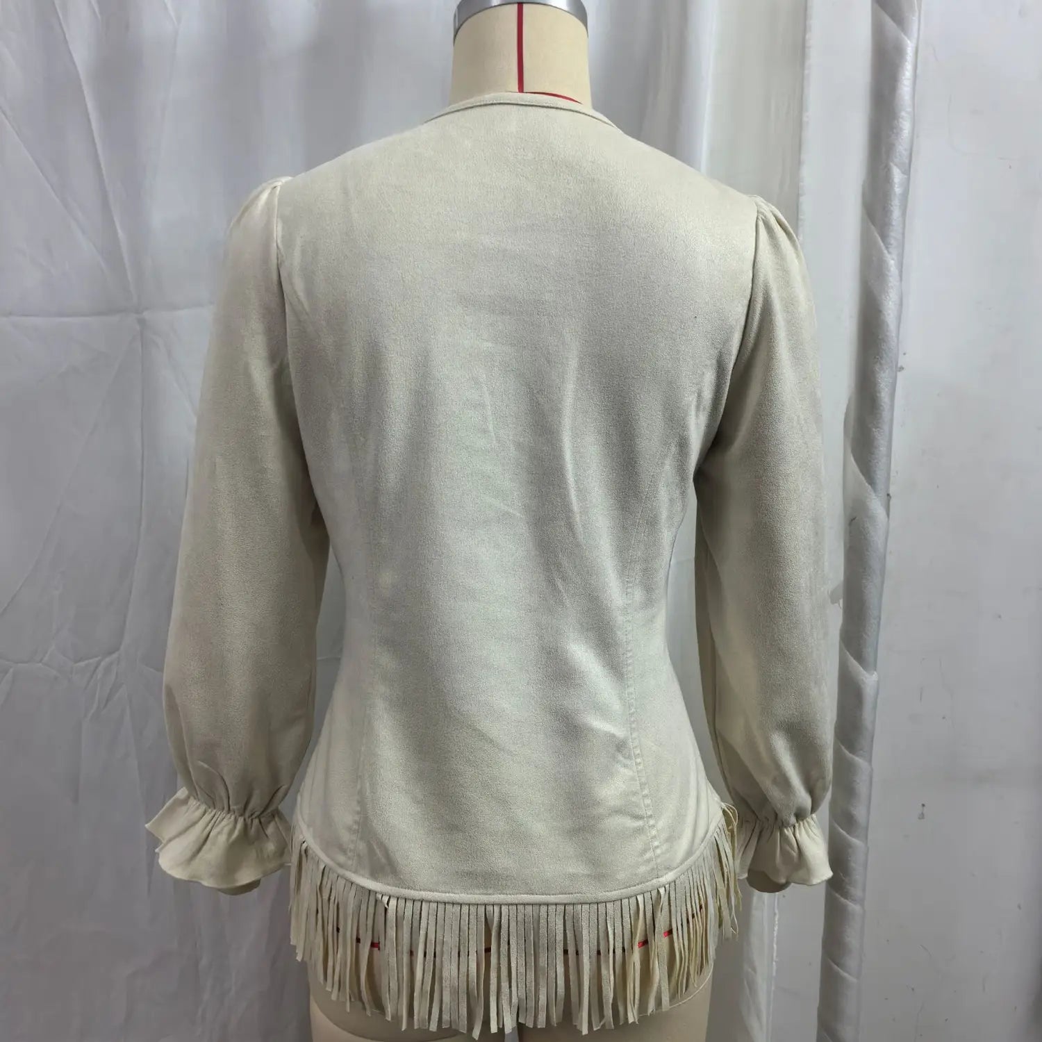 Beige fringe suede v-neck jacket featuring a cream-colored blouse with long sleeves and a fringed hemline.