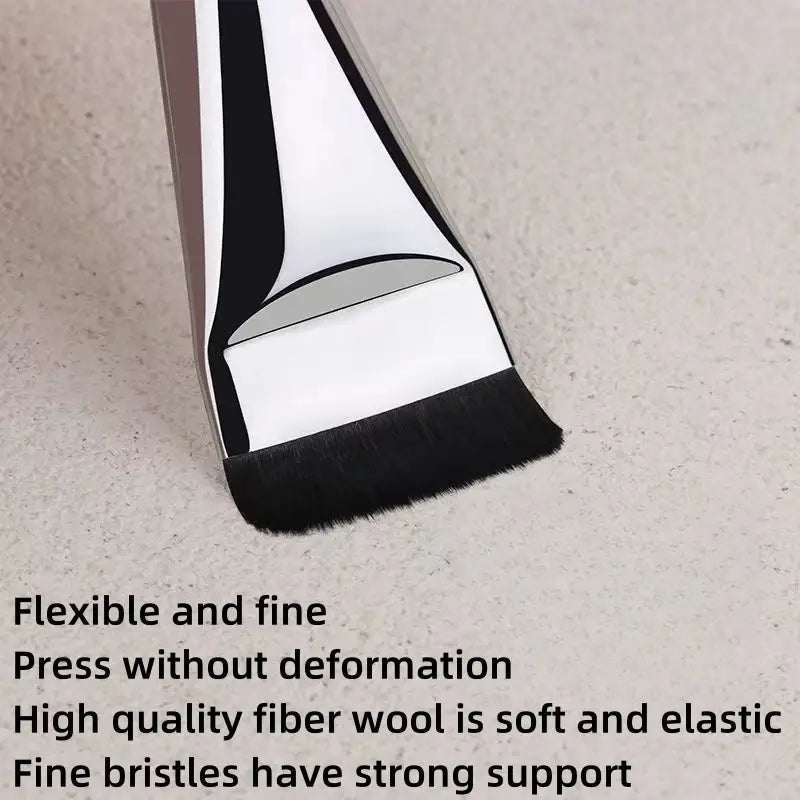 A sleek modern ultra thin foundation brush with a metallic silver handle and black bristles designed as a flat traceless makeup tool.