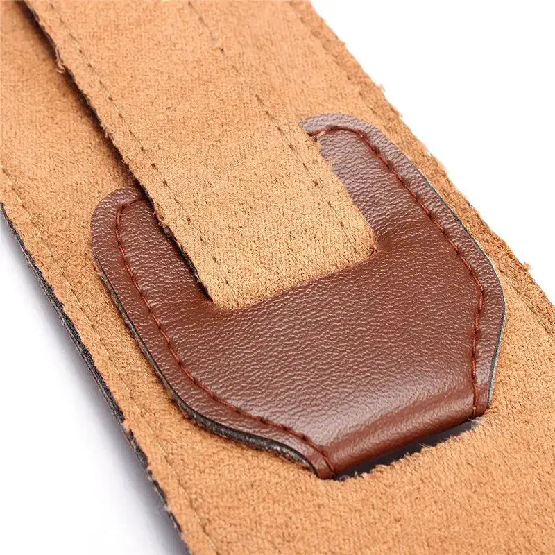 Brown leather belt buckle with textured surface and stitched edges on an adjustable suede lined leather guitar strap 110-130cm.