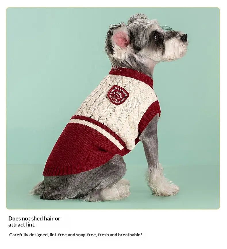 Ein gemütlicher roter und cremefarbener Zopfmuster-Hundepullover aus warmem Material mit passendem Aufnäher auf der Rückseite, entworfen als Schuluniform-Tierbekleidung, von der Rückseite dargestellt.