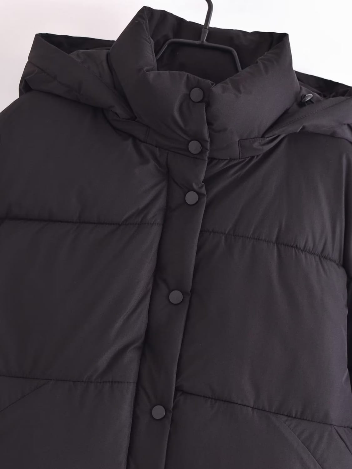 black quilted hooded puffer coat featuring a black puffer jacket with a hood and front button closure.