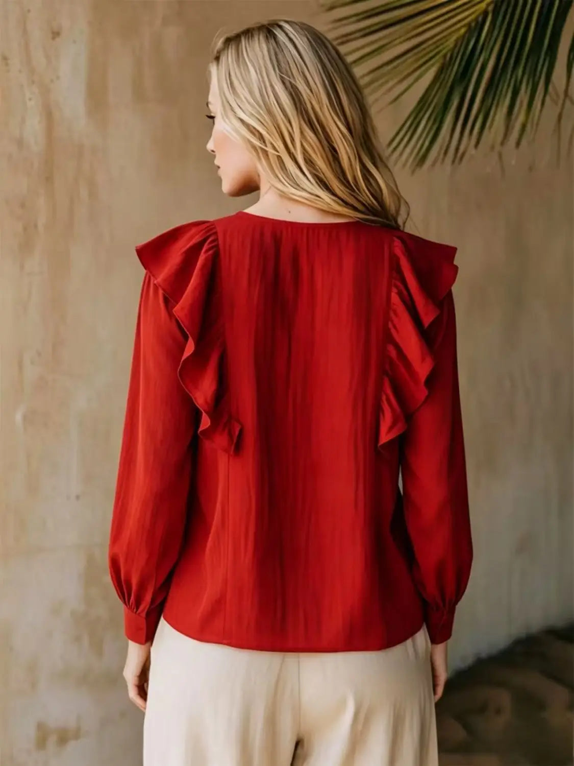Une blouse en lin rouge vif à encolure en V et manches longues, avec des manches à volants délicats et un tissu doux et fluide.