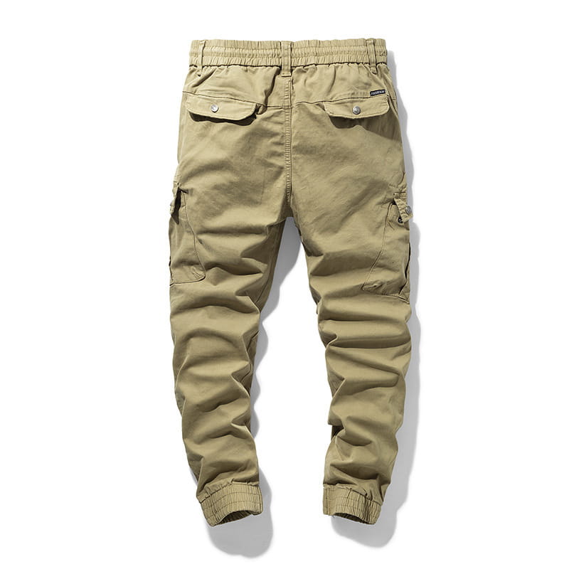 Japanese retro multipocket casual cargo trousers in khaki color with elastic waistband drawstring and multiple button-secured side flap pockets.