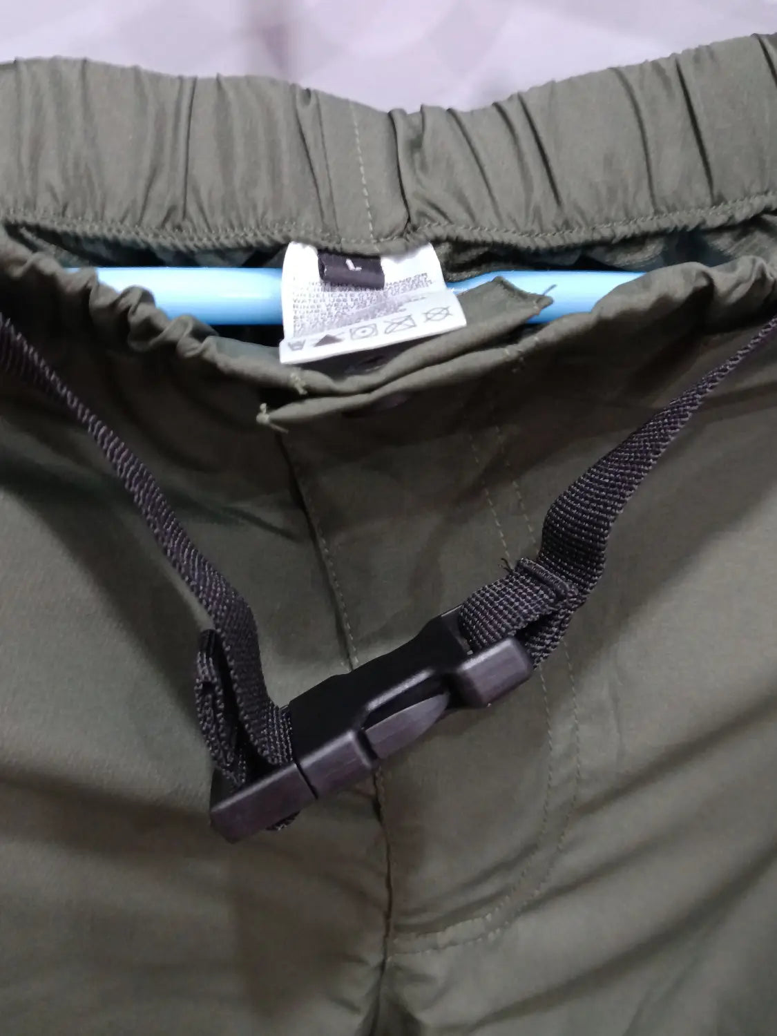 Convertible tactical hiking shorts in olive green nylon featuring a black adjustable drawstring and buckle.