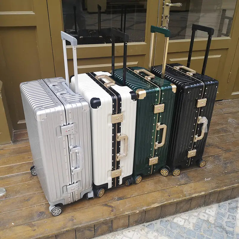 Four hard-shell spinner suitcases in silver white green and black with aluminum alloy frames gold-tone hardware and retractable handles.