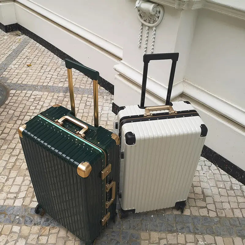 two hard-shell spinner suitcases with aluminum alloy frames in deep green with gold-tone hardware and white with black accents and matching gold-tone handles