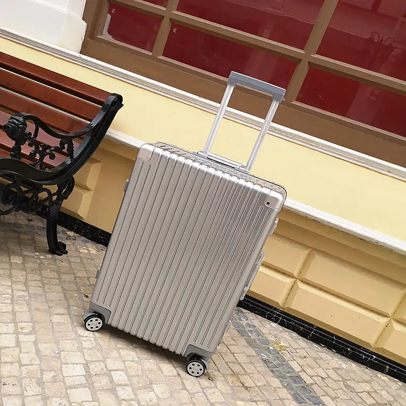 Silver ribbed hard-shell suitcase with aluminum alloy frame retractable handle and four spinner wheels for easy mobility.