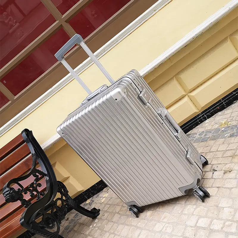 Silver aluminum alloy frame suitcase hard shell spinner luggage with vertical ribbed design and retractable handle.