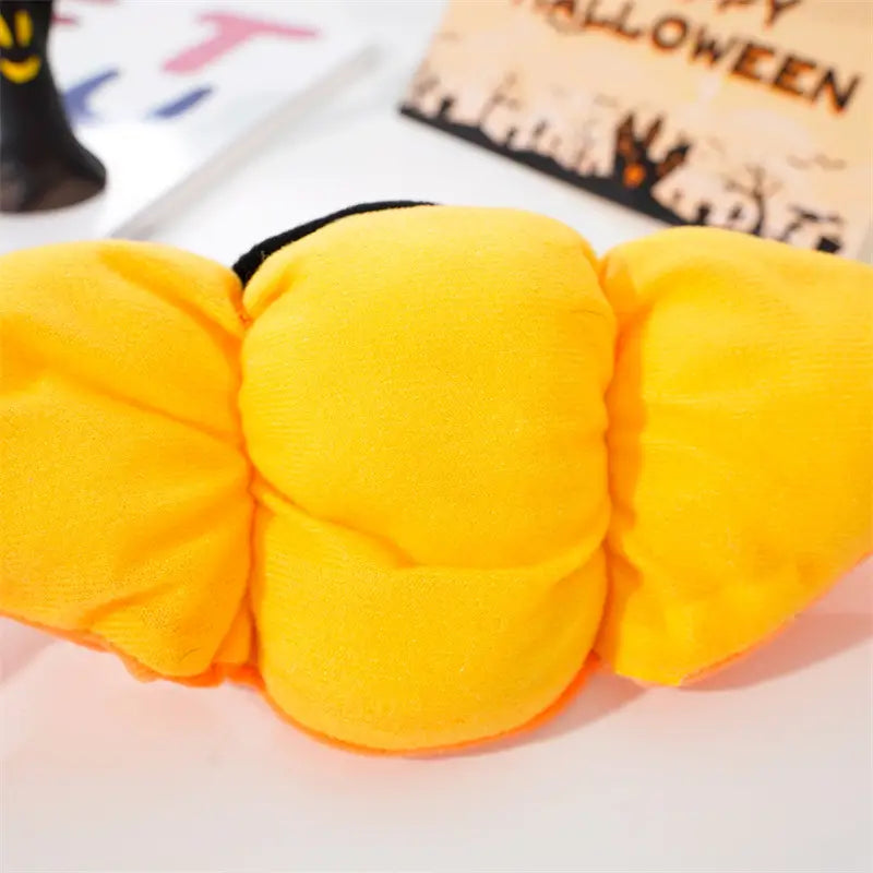 Coussin en peluche orange vif en forme de citrouille, de texture douce et duveteuse, avec une bordure en tissu noir, pour un accessoire de costume de chien en citrouille destiné à Halloween.