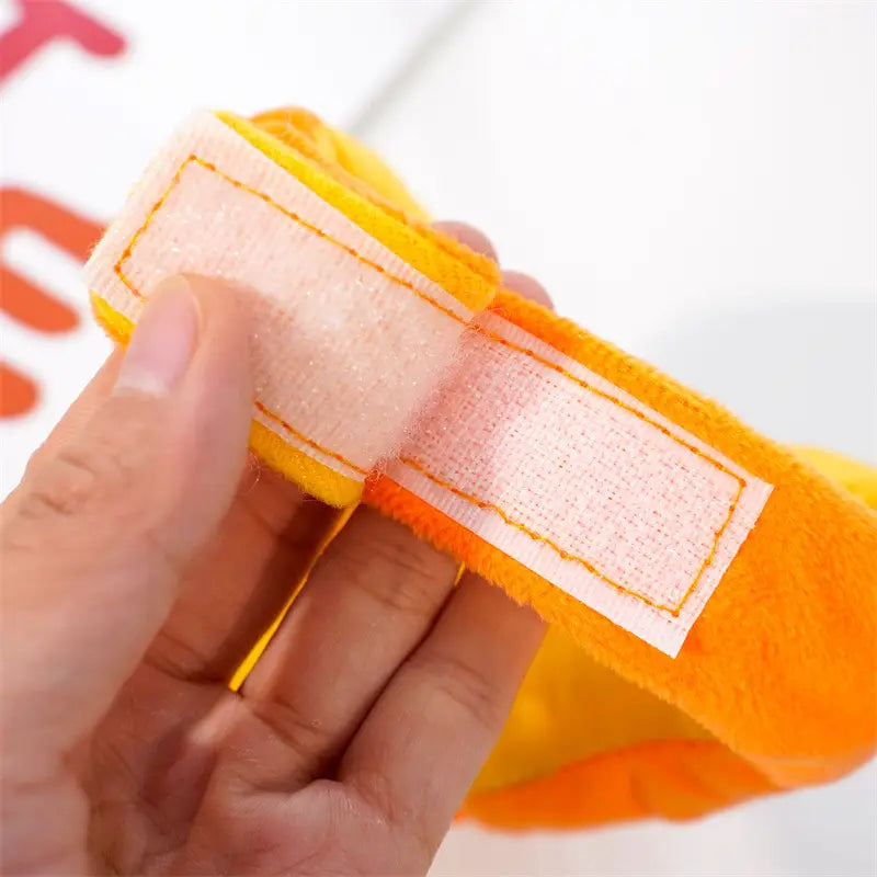 Gant de nettoyage en peluche orange vif, à surface texturée et souple, avec une sangle velcro blanche pour un accessoire de costume de chien en citrouille destiné à Halloween.