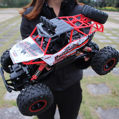 Camion teledirigido RC todoterreno 4WD de alta velocidad en rojo y negro, tipo crawler, con neumáticos resistentes y un chasis detallado para la escalada de rocas.