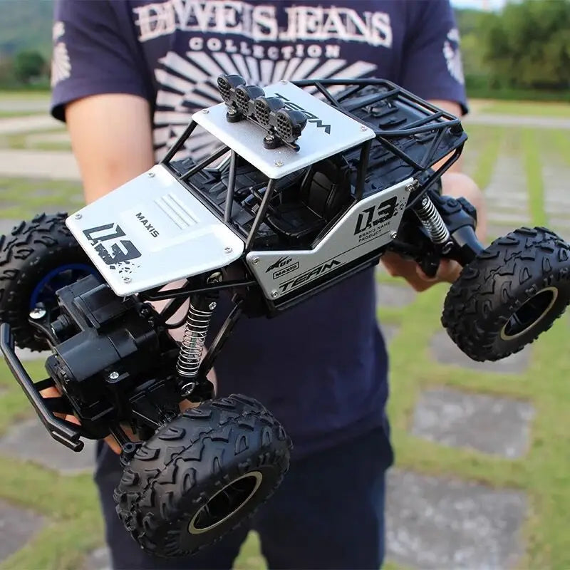 Camion teledirigido RC todoterreno 4WD de alta velocidad en negro y plata, tipo crawler, con neumáticos resistentes, chasis detallado y luces LED en el techo.