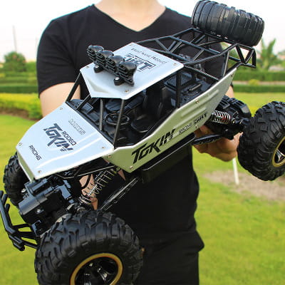 Camion teledirigido RC todoterreno 4WD de alta velocidad en plata y negro, tipo crawler, con neumáticos resistentes y un chasis detallado diseñado para la escalada de rocas.