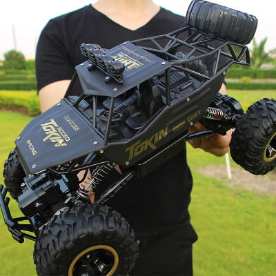 Camion teledirigido RC todoterreno 4WD de alta velocidad en negro y dorado, tipo crawler, con neumáticos resistentes y un chasis detallado diseñado para terrenos difíciles.
