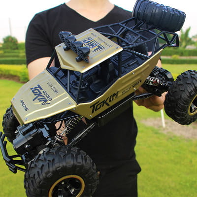 Camion teledirigido RC todoterreno 4WD de alta velocidad en dorado y negro, tipo crawler, con neumáticos resistentes y una suspensión detallada para el terreno de escalada de rocas.
